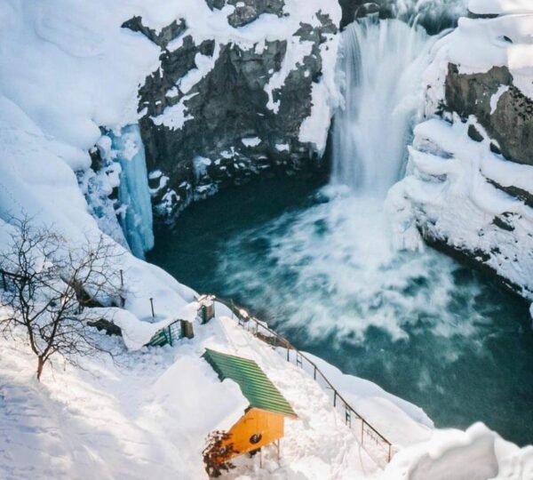 Aharbal Waterfall Kashmir in winter — snow-covered landscape around the Veshaw River with ice-laden pine trees and frozen waterfall creating a magical winter wonderland