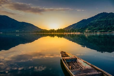 Dal Lake Srinagar at sunrise with traditional Shikara boats gliding across calm turquoise waters