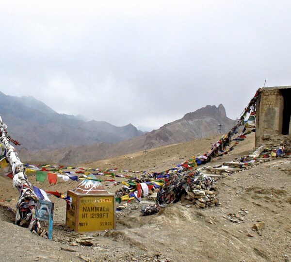 Winding highway crossing Namika La pass with vehicles driving through steep mountain terrain