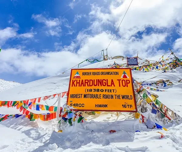At 17582 feet one of world's highest motorable roads with snow covered mountain peaks and road sign